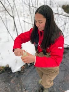 Student testing water sample in stream